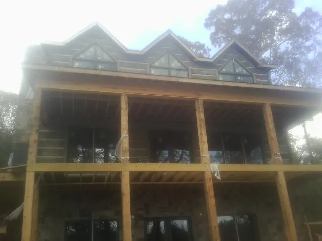 Dormers and porch framing on a large log home under construction — Roof Coating work by our crew in Warsaw